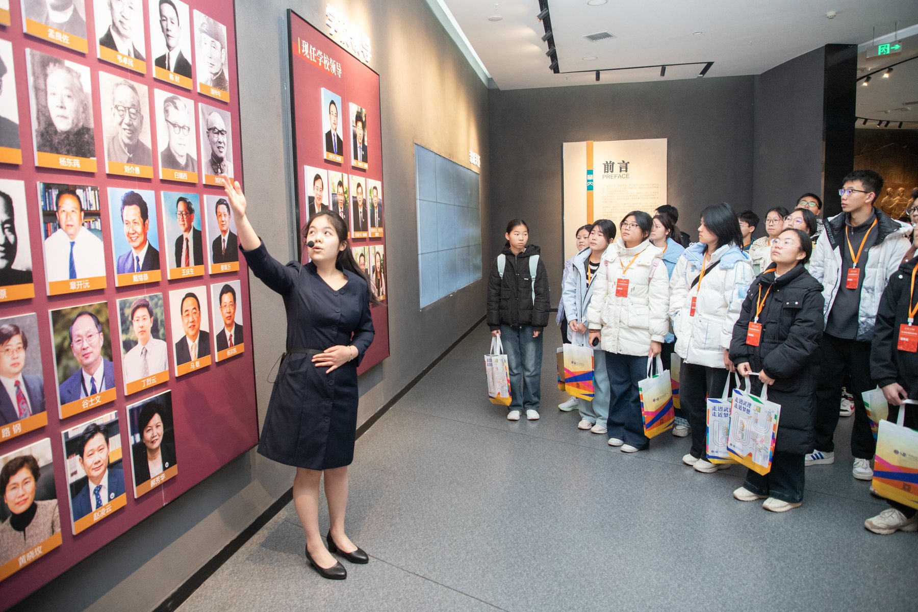 讲解员向中学生介绍大学校史